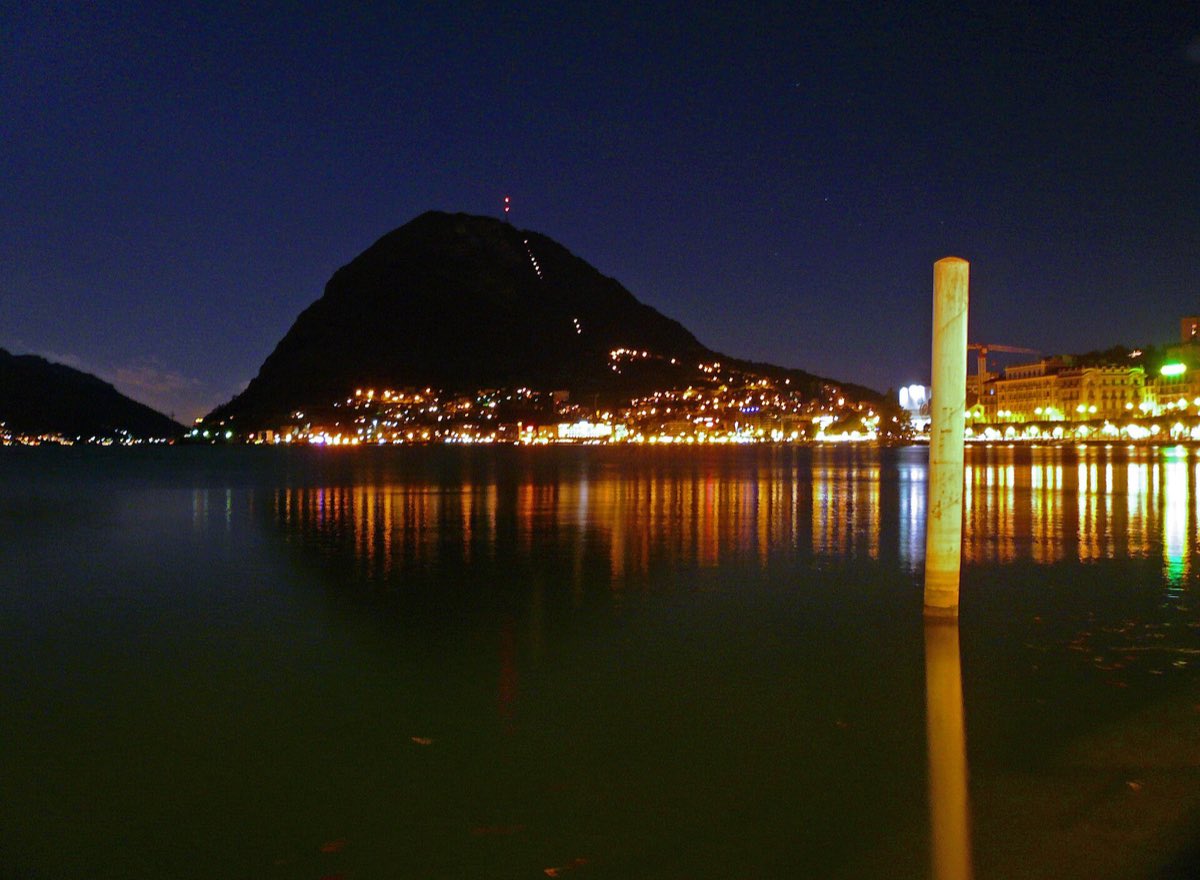 Der Monte San Salvatore und die beleuchtete Uferpromenade von Lugano bei Nacht